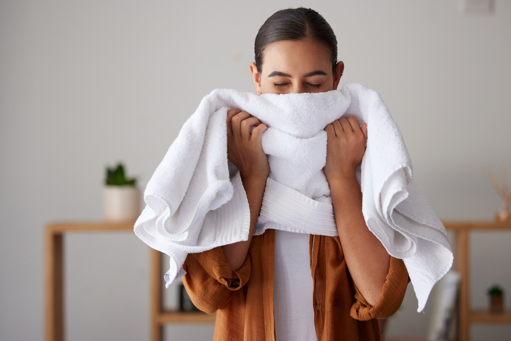 洗濯洗剤アタック抗菌EXで洗濯したタオルの消臭効果を柔軟剤の香りに満足している女性